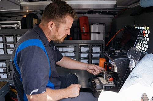 Noble technician cutting a new car key inside their locksmith van